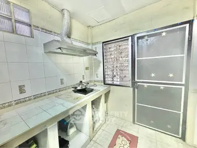 Cozy kitchen with gas stove and ventilation, featuring a secure window and door with starry design.
