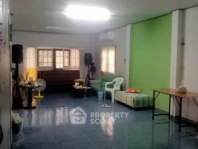 Spacious living room with blue tiled floor and green accent wall, featuring cozy seating and natural light.