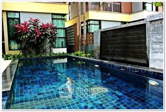 Luxurious modern pool with vibrant blue tiles and lush greenery in a serene residential setting.