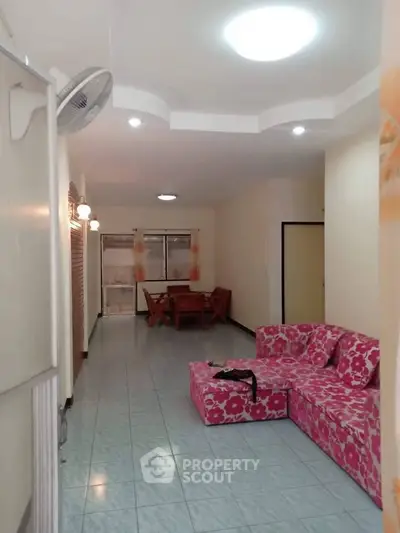 Spacious living room with vibrant pink floral sofa and dining area, ideal for family gatherings.