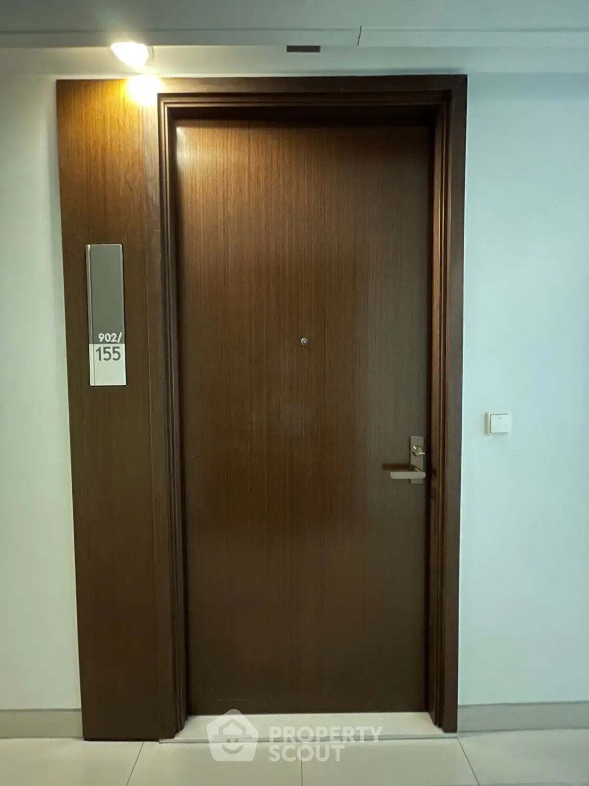 Modern apartment entrance with sleek wooden door and room number 902/155.