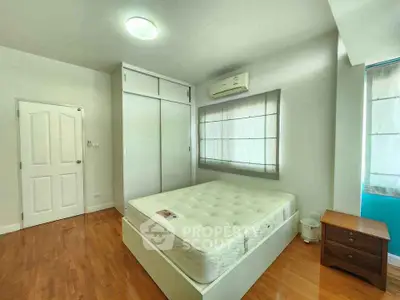 Spacious bedroom with wooden flooring and built-in wardrobe in modern apartment.