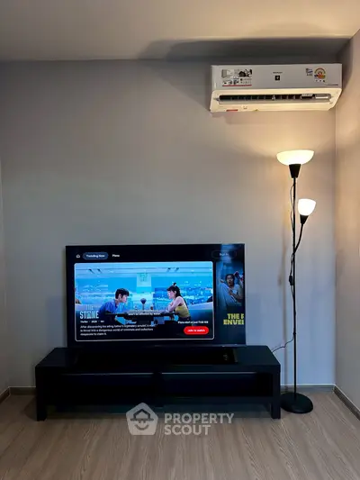 Modern living room with TV, air conditioner, and floor lamp on wooden flooring.