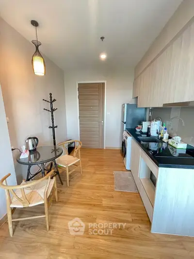 Modern kitchen with wooden flooring, compact dining area, and sleek cabinetry in a cozy apartment.