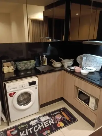 Modern kitchen with washing machine and sleek cabinetry in a cozy apartment setting.