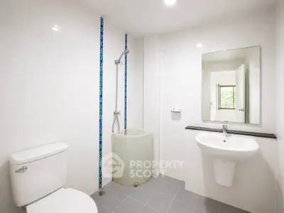 Modern minimalist bathroom with shower, toilet, and sink in bright white tiles.