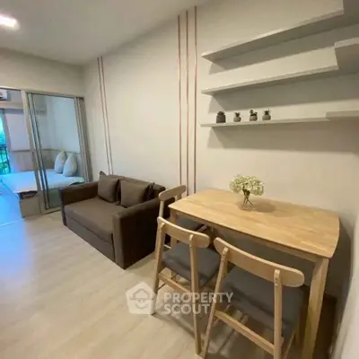 Modern living room with cozy sofa and dining area, featuring sleek shelving and natural light.
