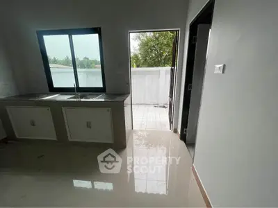 Modern kitchen with sleek design and outdoor access, featuring glossy floors and ample natural light.
