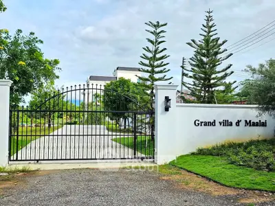 Elegant gated entrance of Grand Villa d' Maalai with lush greenery and modern architecture.