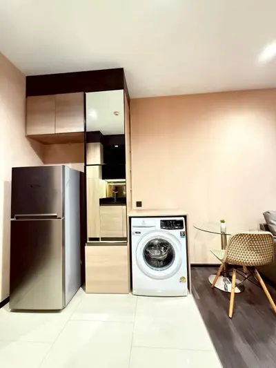 Modern kitchen with stainless steel fridge and washing machine in stylish apartment.