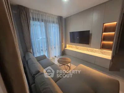 Modern living room with sleek design, featuring a wall-mounted TV and elegant curtains.