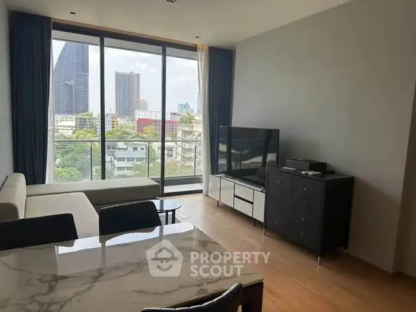 Modern living room with large windows offering city skyline view, sleek furniture, and elegant decor.