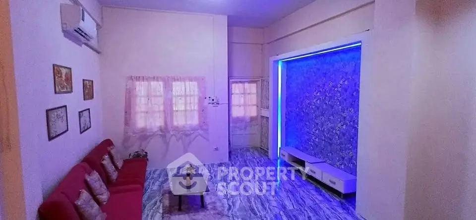 Stylish living room with modern decor and vibrant lighting, perfect for relaxation and entertainment.