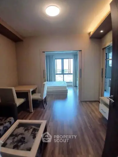 Cozy apartment with open layout and wooden flooring, featuring a bright living area and bedroom.