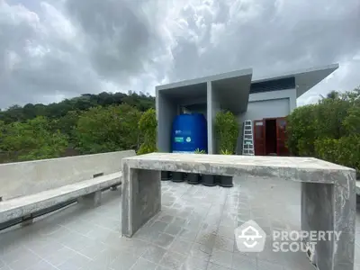 Modern rooftop with concrete seating and lush greenery under cloudy sky