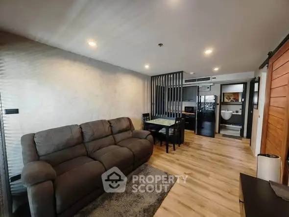 Modern living room with cozy sofa and dining area, featuring stylish wooden flooring and contemporary decor.