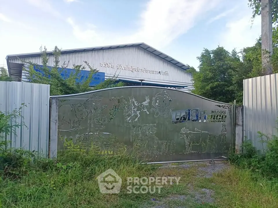 Industrial warehouse with metal gate and lush greenery surroundings