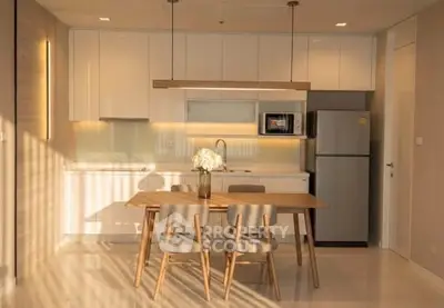 Modern kitchen with sleek cabinetry and dining area, featuring natural light and contemporary design.