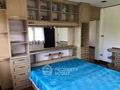 Spacious bedroom with built-in wooden storage and large mirror