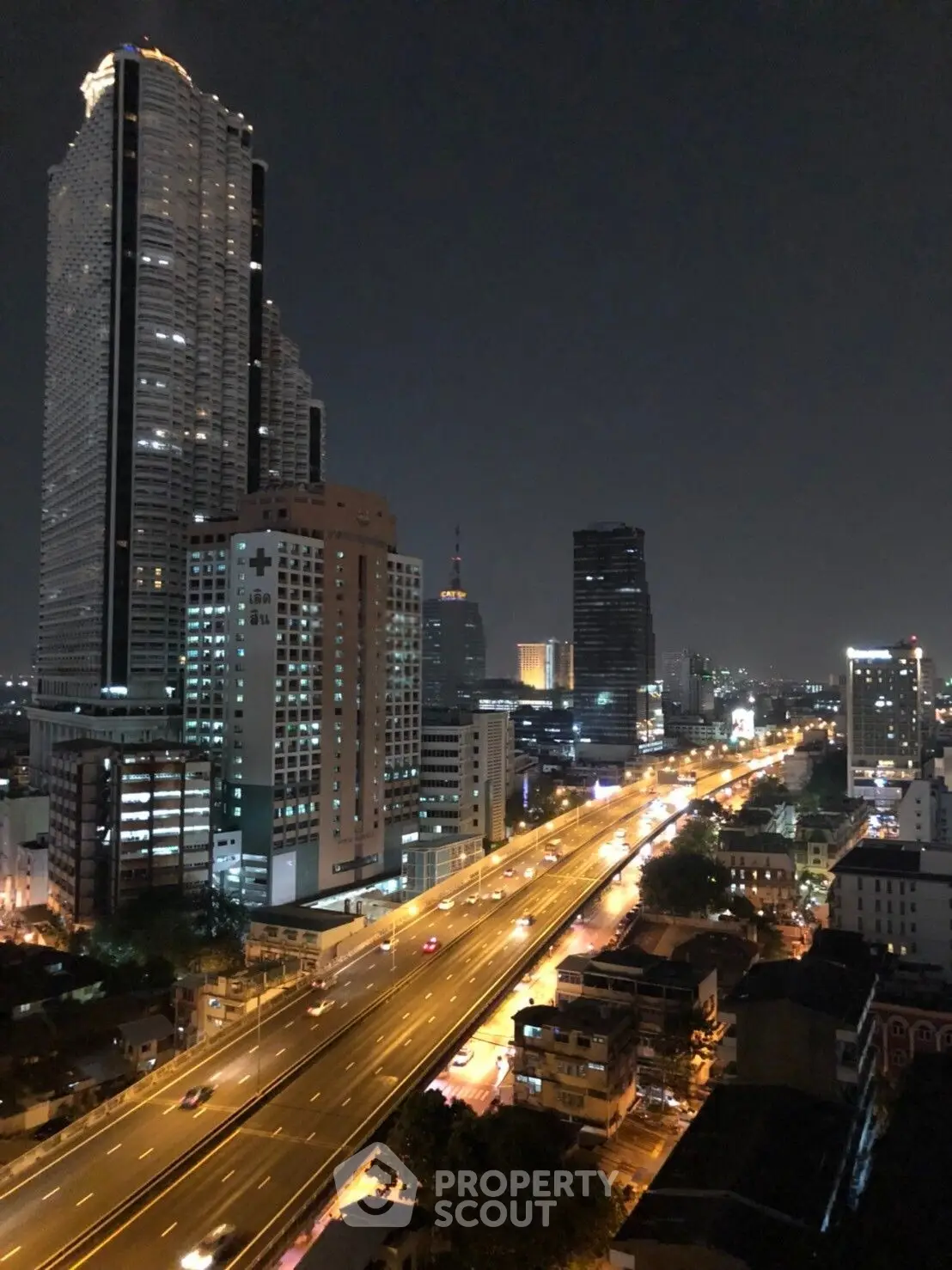 Stunning nighttime cityscape view with illuminated skyscrapers and bustling highway.