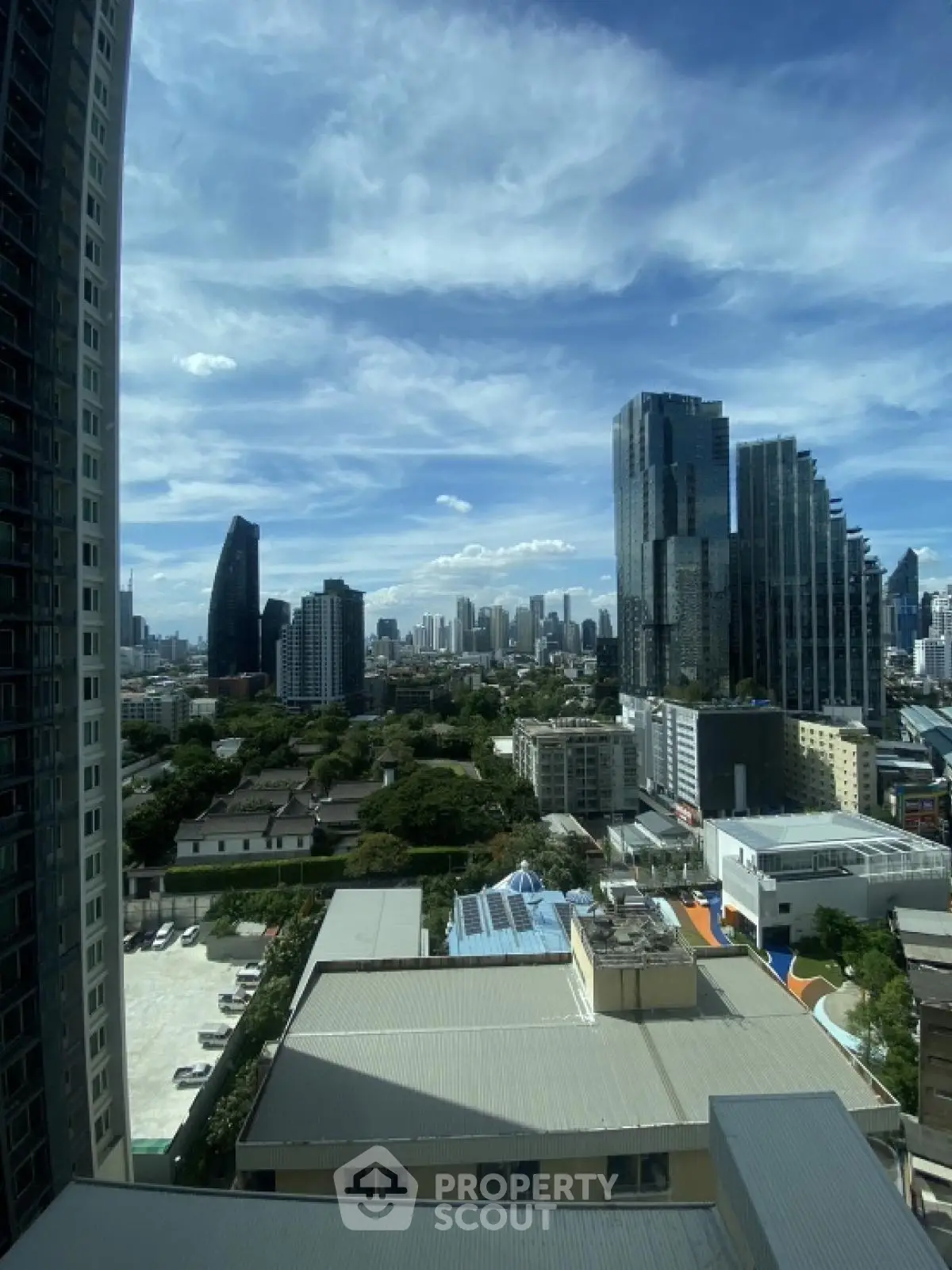 Stunning cityscape view from high-rise building with lush greenery and modern architecture.