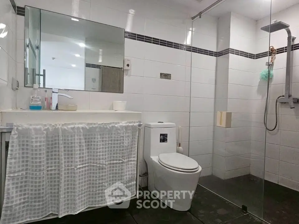 Modern bathroom with glass shower and sleek fixtures in contemporary home.