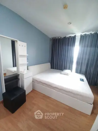 Modern bedroom with stylish blue accent wall and sleek furniture, perfect for a cozy retreat.