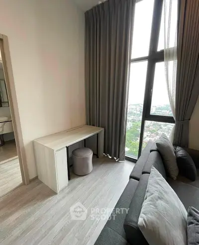 Modern living room with large window and stylish furniture offering a stunning city view.