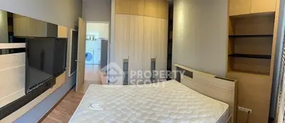 Modern bedroom with built-in wardrobe and wall-mounted TV, featuring a glimpse of laundry area.