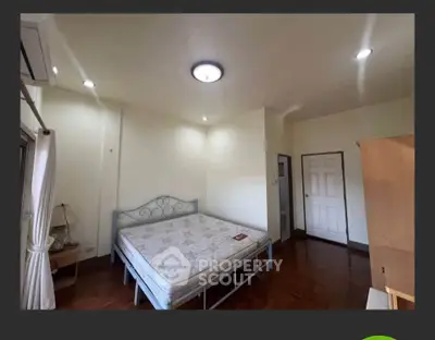 Spacious bedroom with wooden flooring and natural light in modern apartment.