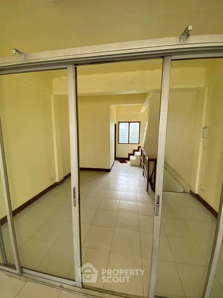 Spacious interior with sliding glass doors and tiled flooring, ideal for versatile living space.