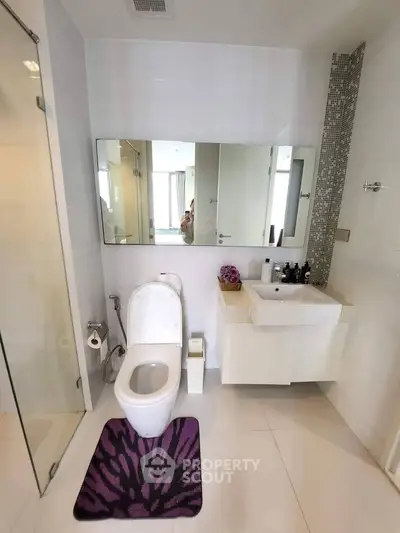 Modern bathroom with sleek fixtures and stylish decor, featuring a large mirror and elegant sink.