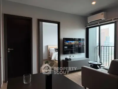 Modern living room with balcony view and wall-mounted TV in a stylish apartment.