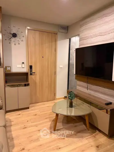 Modern living room with stylish decor and wooden flooring, featuring a wall-mounted TV and contemporary furniture.