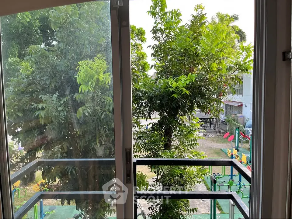 Charming balcony view with lush greenery and outdoor play area, perfect for nature lovers.