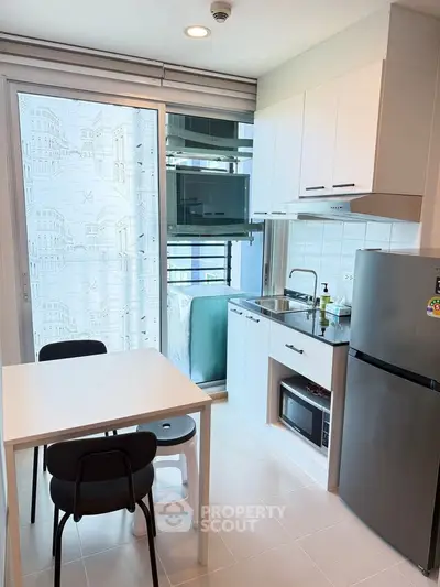 Modern compact kitchen with dining area and balcony view in urban apartment
