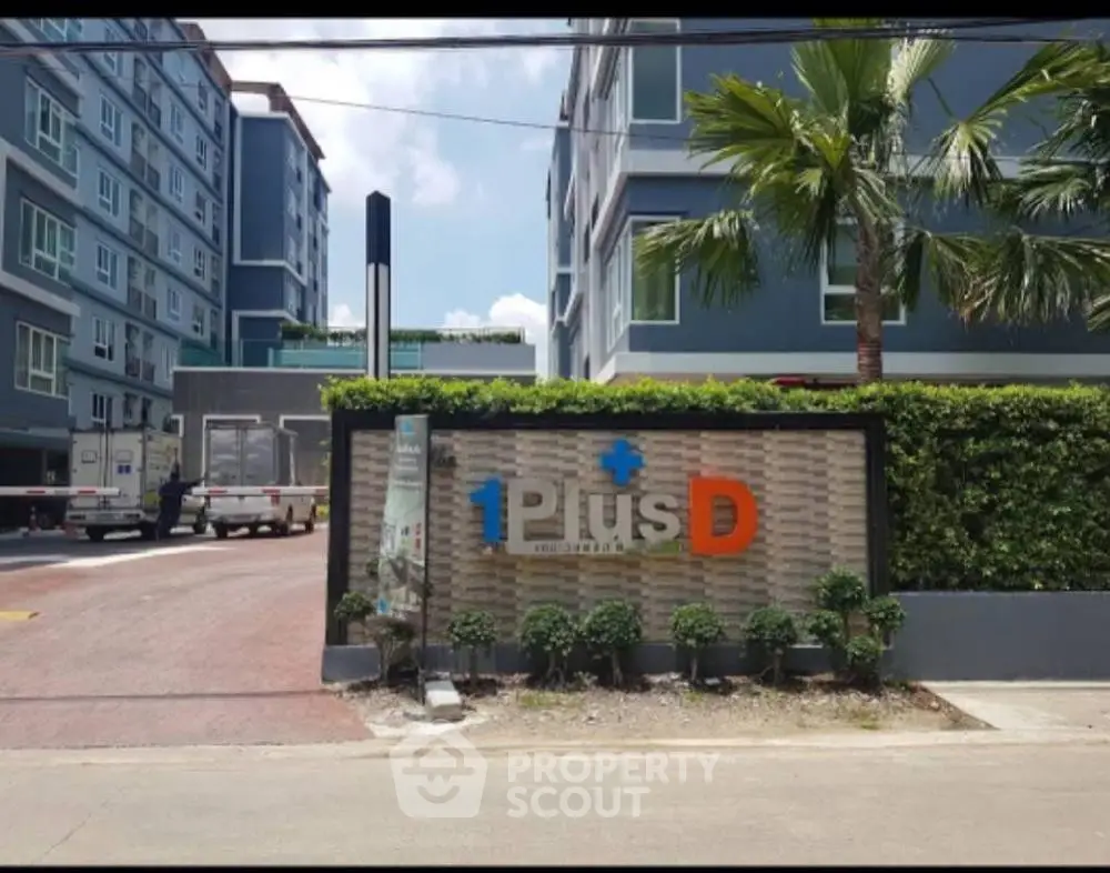 Modern condominium entrance with lush greenery and clear signage, showcasing urban living.