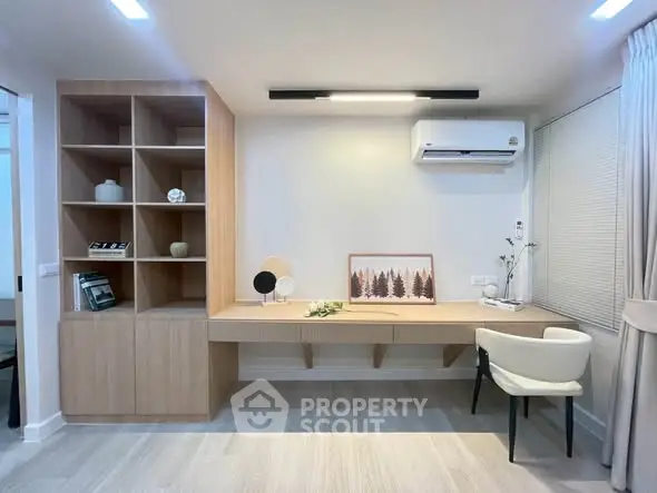 Modern study room with built-in wooden shelves and desk, featuring minimalist decor and air conditioning.