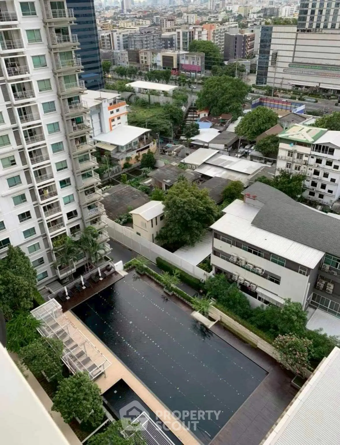 Stunning aerial view of urban residential complex with pool and lush greenery, perfect for modern living.