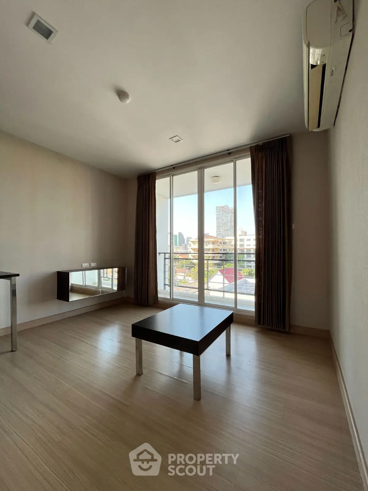 Spacious living room with large windows and city view, featuring modern minimalist decor.