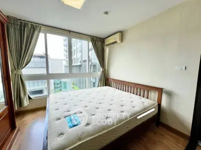 Bright bedroom with large window and wooden bed frame in modern apartment.