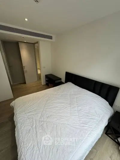 Modern bedroom with minimalist design and cozy atmosphere, featuring a comfortable bed and sleek furnishings.