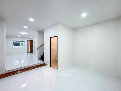 Spacious modern interior with white walls and glossy floors, featuring a staircase and open layout.