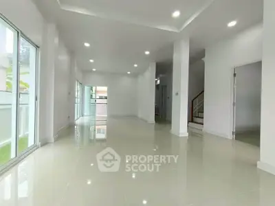 Spacious modern living room with glossy tile flooring and ample natural light.