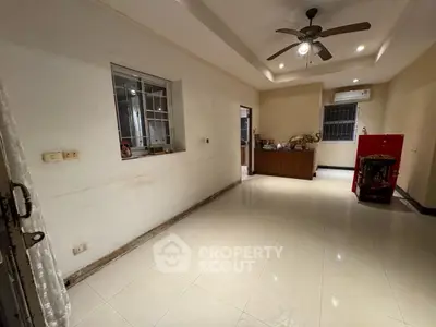 Spacious living room with ceiling fan and tiled flooring in modern home