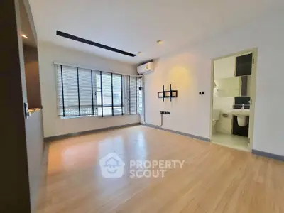 Spacious unfurnished living room with wooden flooring and large windows in modern apartment.
