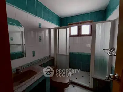 Charming bathroom with teal tiles and modern shower enclosure