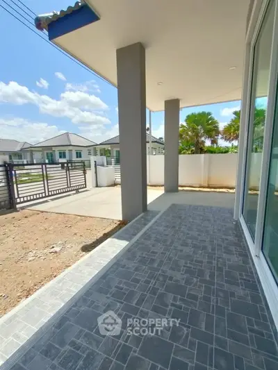 Spacious modern patio with tiled flooring and garden view in sunny residential area.