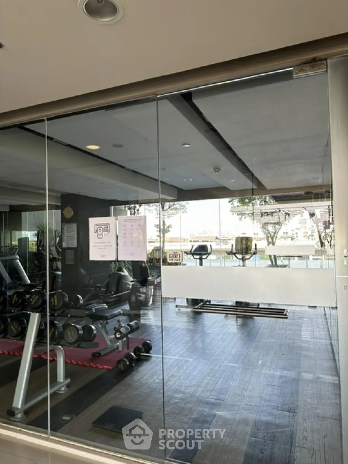 Modern gym with glass walls and fitness equipment in luxury apartment complex