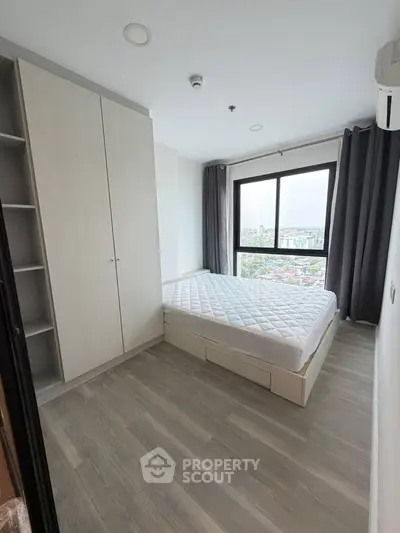 Modern bedroom with large window and city view, featuring sleek wardrobe and minimalist design.